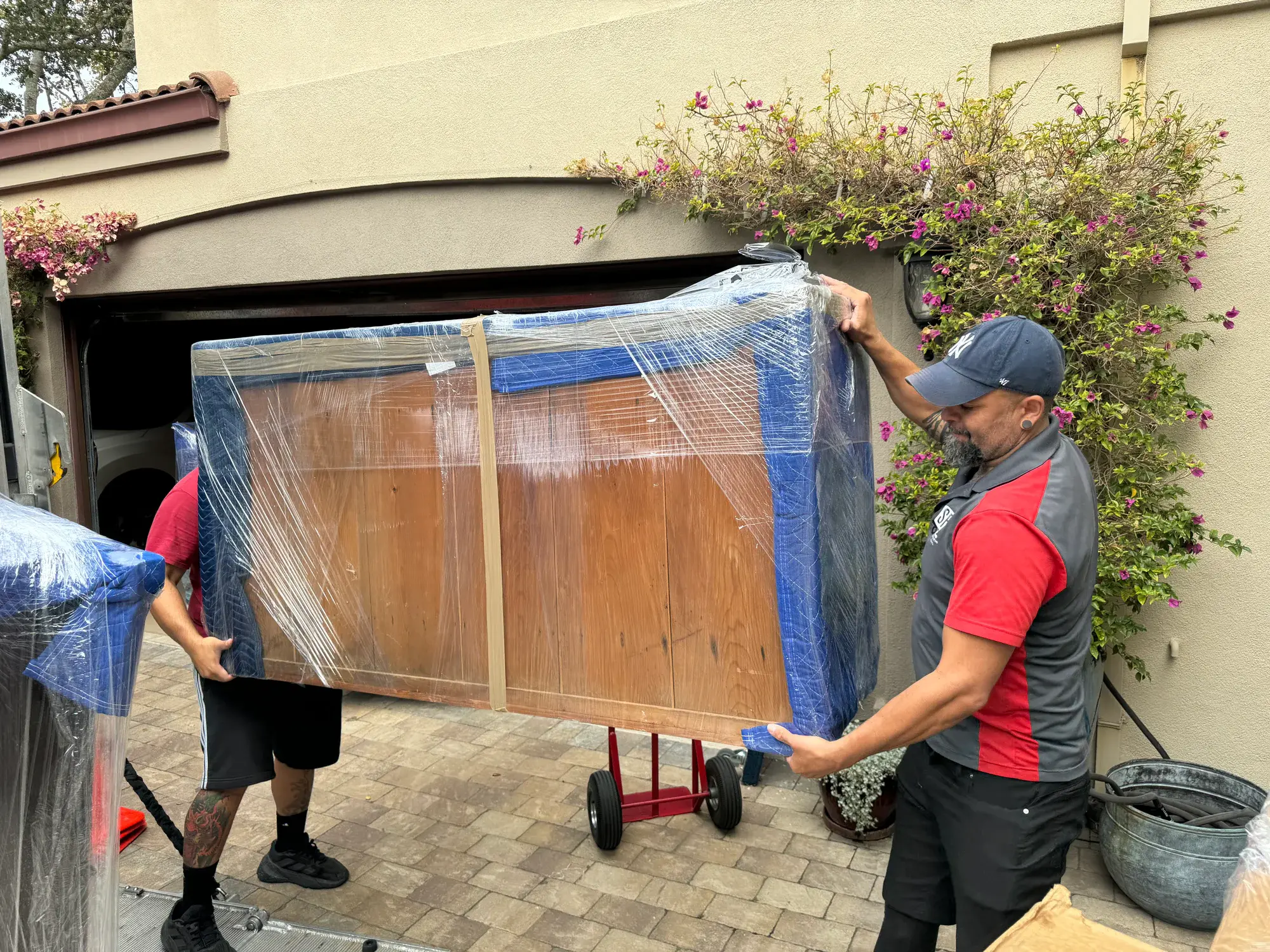 SF Bay Area Moving crew carrying wrapped furniture from a residential garage
